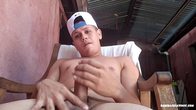 Latin boy Arthur seated in chair, pulling out fat uncut cock from shorts to play with. By the time big dick is hard, young man is naked and ready to beat off.