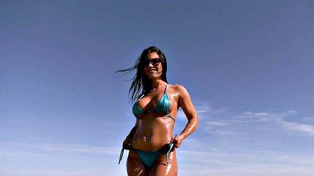 Watch this tattooed Latina babe oil up and take a big hard cock on the beach