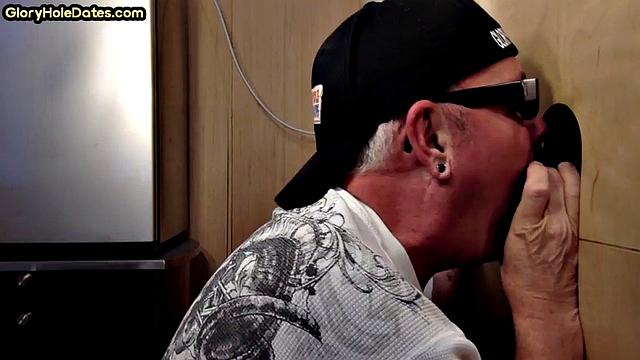 парень сосёт чёрный член в глори-холе и дрочит