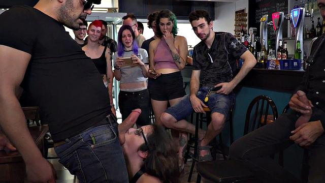 Public BDSM babe deepthroats hard cock in front of onlookers