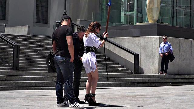 Public BDSM babe deepthroats hard cock in front of onlookers