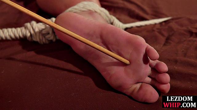 Lezdom bastinado for hardtied slut