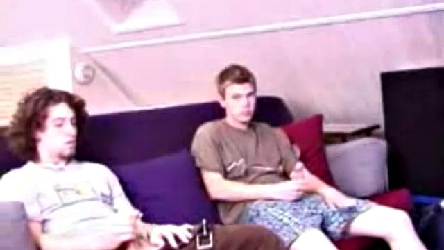 Adam and Christian sit next to each other on the couch watching a porno. They unzip and stoke for a bit, before taking turns sucking each other's hard cock.