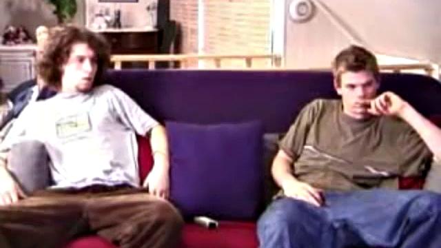 Adam and Christian sit next to each other on the couch watching a porno. They unzip and stoke for a bit, before taking turns sucking each other's hard cock.