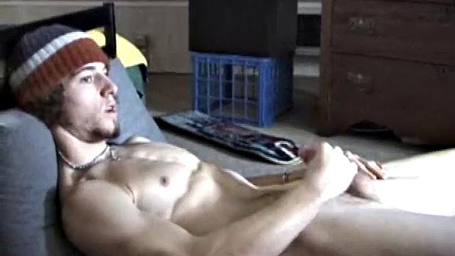Adam relaxes on the floor watching porn video, strokes cock, plays with butthole, and blasts cum load onto skateboard