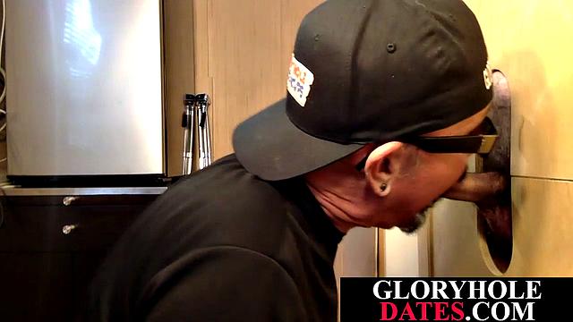 Inked mature blowing black cock through gloryhole