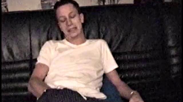 Kicking back on the couch, Dominic mugs a bit for the camera, as he flips through some porn mags for a little inspiration. He's pretty chatty at first, but gets quieter as he admires his hard dick and gets busy stroking it.