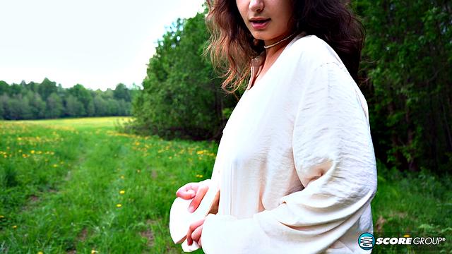 Busty teenage brunette Lola exposes DD-cup tits in open field and spreads pussy for pleasure.