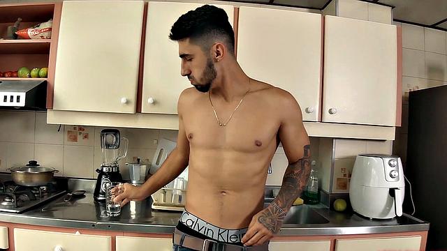 We find Julian in the kitchen, as his clothes slowly hit the floor. He pushes his pants and underwear down and a big boner pops out. Once Julian is completely naked, he leans against a counter and starts jacking off.