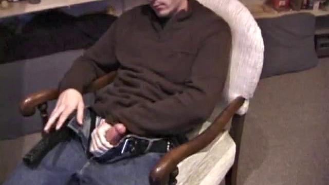 By the time the camera finds him, Dan is already going for his woody. He seems uncomfortable in the chair, so he stands up and moves to the staircase, where we can see his cock getting harder and harder.