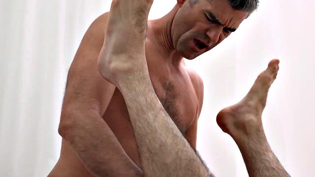 Hairy preacher top gets drilled by a bareback twink while giving a handjob in the kitchen