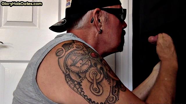 Gaydaddy with tattoos sucks hard cock in gloryhole