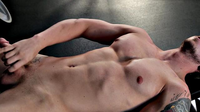 Tattooed stud masturbating in the gym