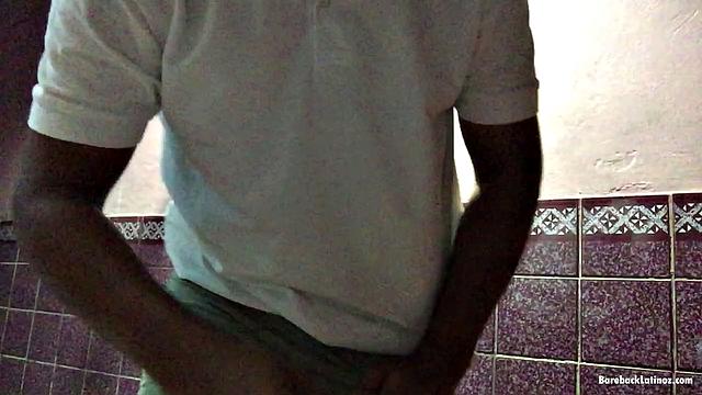 In a dark hallway, Avrool stands under a light and starts stroking that big uncut cock of his.