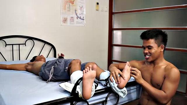 Jacob has his sexy buddy Simon spreadeagled on the bed for some tickling fetish action. Jacob loves tickling so he spends plenty of time on those Asian boy feet. But that's not to say Simon isn't ticklish on his upper body.