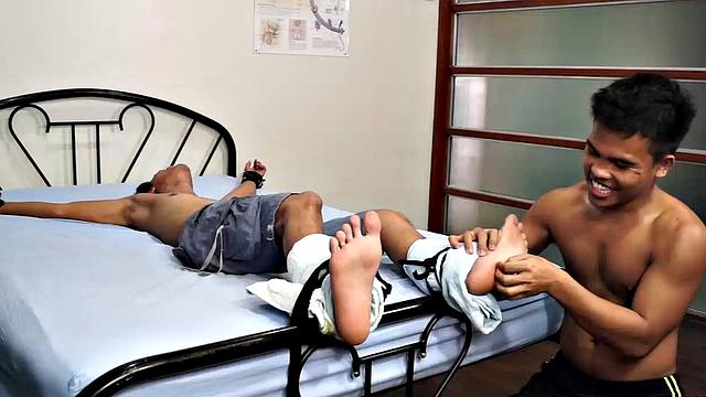 Jacob has his sexy buddy Simon spreadeagled on the bed for some tickling fetish action. Jacob loves tickling so he spends plenty of time on those Asian boy feet. But that's not to say Simon isn't ticklish on his upper body.