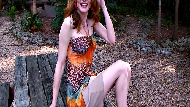 Hot redheaded MILF Lorelei strips nude outdoors and uses a dildo on her pussy on a bench.