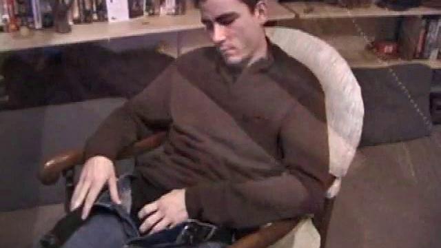 By the time the camera finds him, Dan is already going for his woody. He seems uncomfortable in the chair, so he stands up and moves to the staircase, where we can see his cock getting harder and harder.