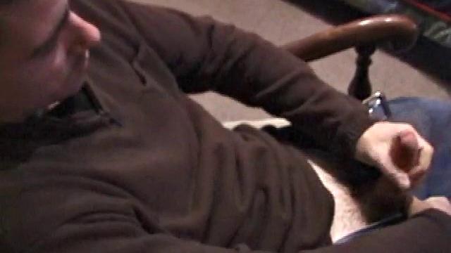 By the time the camera finds him, Dan is already going for his woody. He seems uncomfortable in the chair, so he stands up and moves to the staircase, where we can see his cock getting harder and harder.