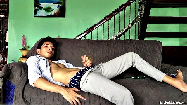 On a sofa, Santiago slowly strips down and pulls his big uncut cock out. The slim Latino never gets completely naked, as he beats off with determination.