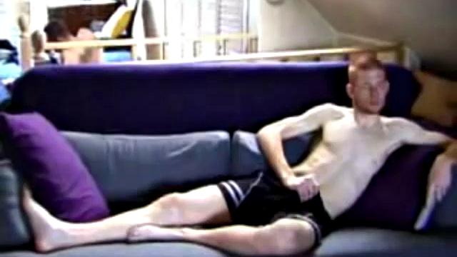 Shane and Tristian are talking about how horny the video is making them when they decide to relieve the pressure. Shane gets up and moves to the bed, while Tristian strokes his cock on the sofa.