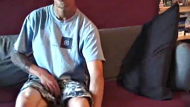 Young amateur Brandon reclines on the sofa and pulls off his pants. Watching porn video, he rubs his dick hard and fingers his asshole.