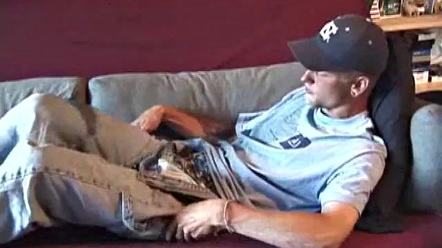 Young amateur Brandon reclines on the sofa and pulls off his pants. Watching porn video, he rubs his dick hard and fingers his asshole.