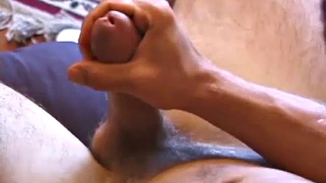 Brocks pops in a porn video and starts to strip. The man sports a hard cock, stroking it before exploding on his face and chest.