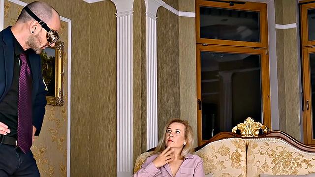 Watch as a mature blonde seduces her young guest with her natural tits and glasses on the couch