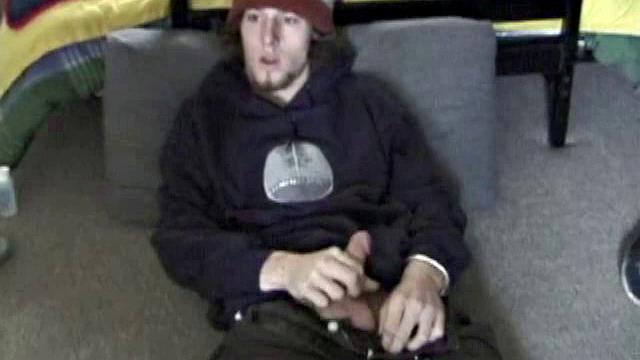 Adam relaxes on the floor watching porn video, strokes cock, plays with butthole, and blasts cum load onto skateboard