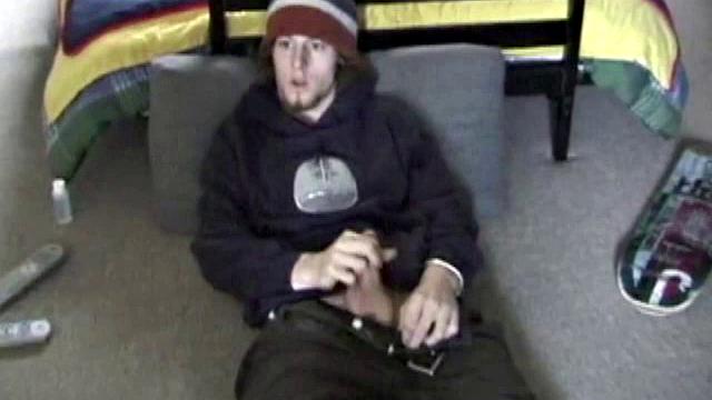 Adam relaxes on the floor watching porn video, strokes cock, plays with butthole, and blasts cum load onto skateboard