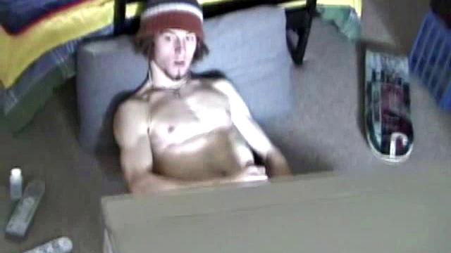 Adam relaxes on the floor watching porn video, strokes cock, plays with butthole, and blasts cum load onto skateboard