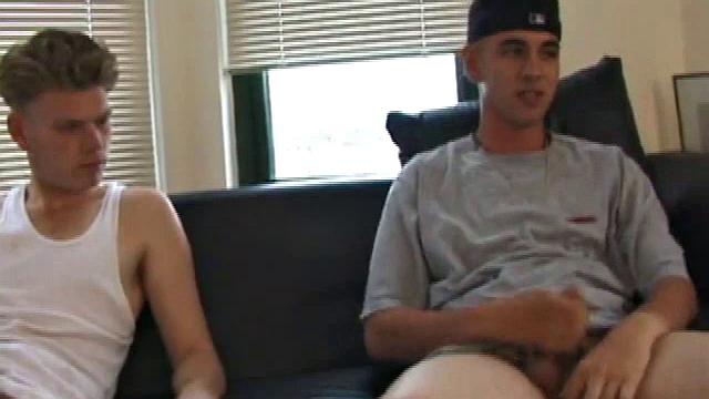 Christian and Richie sit on the sofa, watching a porn video while slowly rubbing their crotches. Richie shyly takes out his dick and watches as Christian strips off his shorts and exposes an impressive cock.