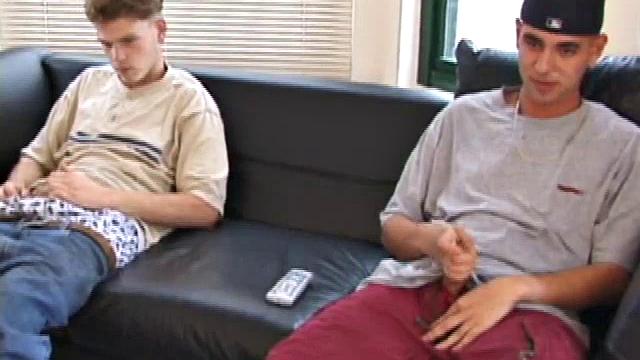 Christian and Richie sit on the sofa, watching a porn video while slowly rubbing their crotches. Richie shyly takes out his dick and watches as Christian strips off his shorts and exposes an impressive cock.