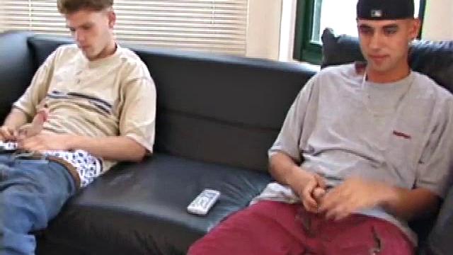 Christian and Richie sit on the sofa, watching a porn video while slowly rubbing their crotches. Richie shyly takes out his dick and watches as Christian strips off his shorts and exposes an impressive cock.