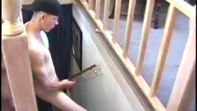 Dressed in baggy shorts and a baseball cap, popular Shane stands halfway up the stairs, watching his porno and talking about making the wall the target for his cum shot.