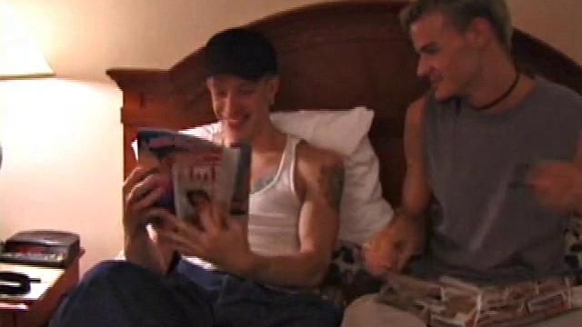 Derrick Hanson throws a porn magazine to Shane and keeps a magazine for himself. Lying on the hotel bed together they flip through the pictures of the magazines showing each other what pictures are turning them on.