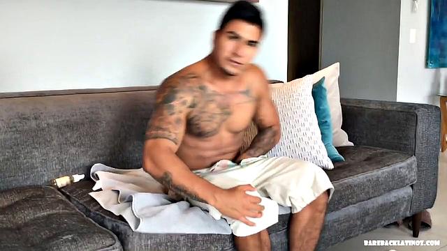 Our featured solo of the week is Erick, a big and muscular Latino with a serious look on his face. Seated on a sofa, it doesn't take long for him to get naked.