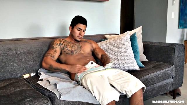 Our featured solo of the week is Erick, a big and muscular Latino with a serious look on his face. Seated on a sofa, it doesn't take long for him to get naked.