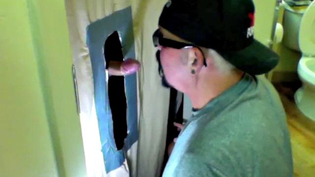 Чёрный член получает минет через дырку в стене