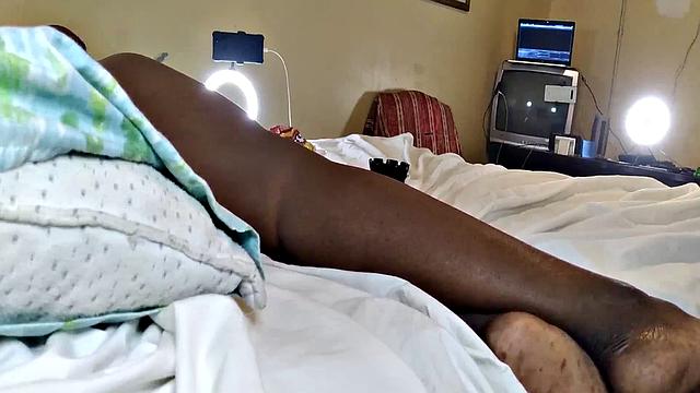 черная зрелая развалилась на кровати и дрочит гладкую киску