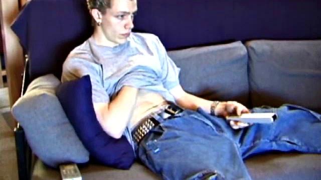 Young Shane relaxes on the sofa while watching a porn video and gets totally into himself. He delivers a nice long stroke show, before shooting onto his t-shirt.