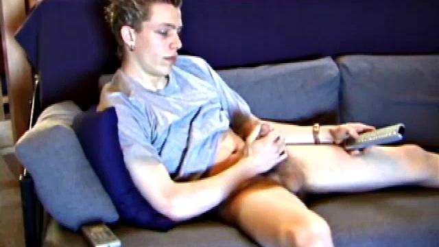 Young Shane relaxes on the sofa while watching a porn video and gets totally into himself. He delivers a nice long stroke show, before shooting onto his t-shirt.