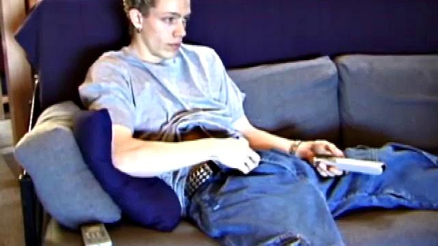 Young Shane relaxes on the sofa while watching a porn video and gets totally into himself. He delivers a nice long stroke show, before shooting onto his t-shirt.