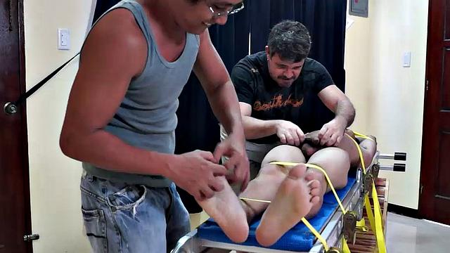 Diamond collectors have captured a thief who's been stealing diamonds from them. They've strapped him down on a rack and intend to tickle the cute young Asian boy until he breaks. They've got all day if necessary.