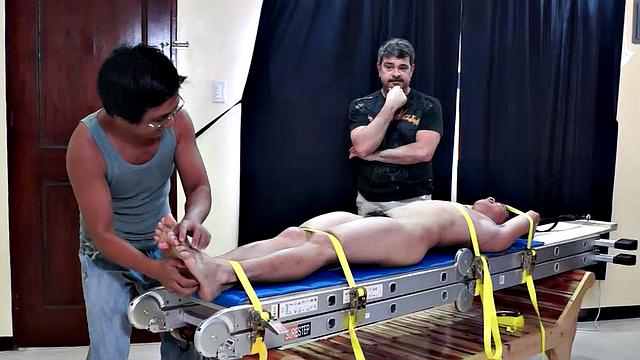 Diamond collectors have captured a thief who's been stealing diamonds from them. They've strapped him down on a rack and intend to tickle the cute young Asian boy until he breaks. They've got all day if necessary.