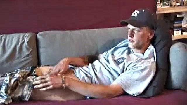 Young amateur Brandon reclines on the sofa and pulls off his pants. While watching a video, he rubs his cock hard and fingers his ass.