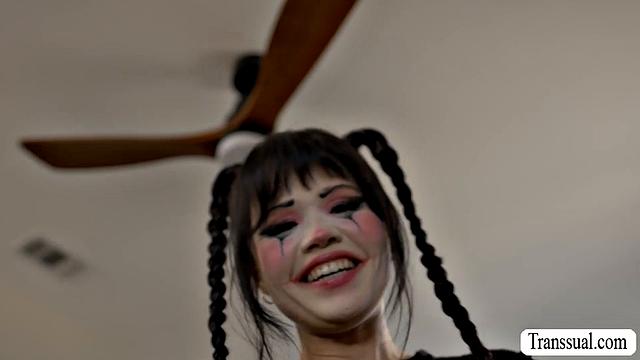 Пышногрудая клоунесса сосёт член своей транс-соседки и даёт ей трахнуть себя в киску, пока та мастурбирует на кровати.