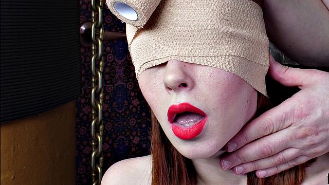 Redhead slavegirl gags on a big cock while blindfolded and tied up in backstage sex-toy action