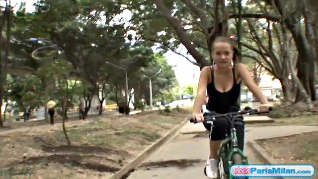 Busty teen riding her bike through the park